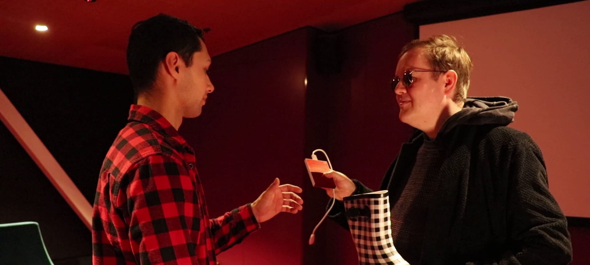 A mysterious man offers a hard drive in one hand and a gumboot in the other to another man