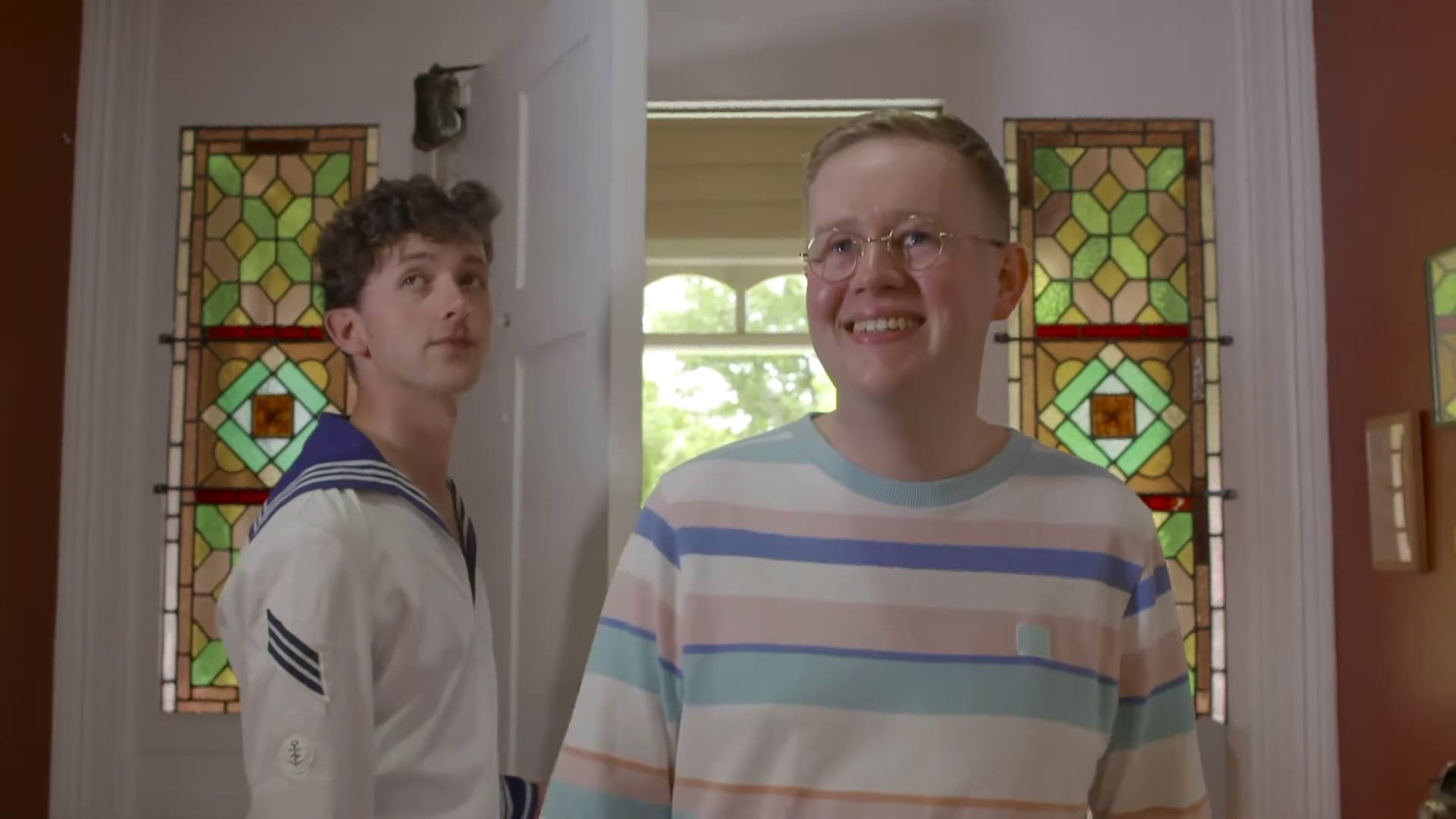 Two young men. One has just let the other into an old house.