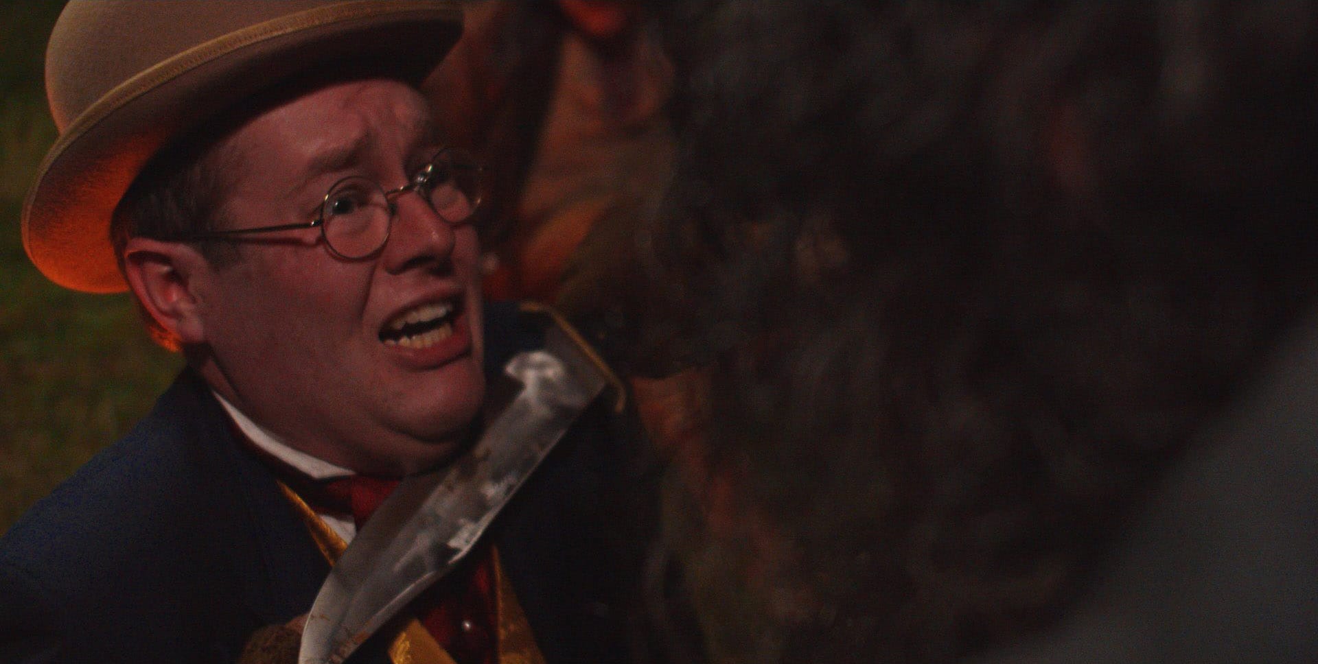 Ostentatiously dressed 19th-century man with a knife to his throat.